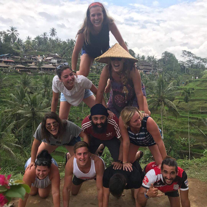 Group of people forming a human pyramid in a lush landscape.