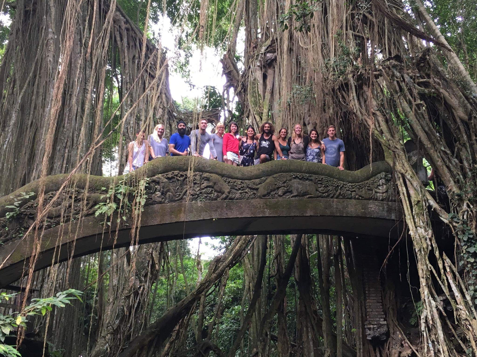 Group of people on a decorative bridge in a forest.