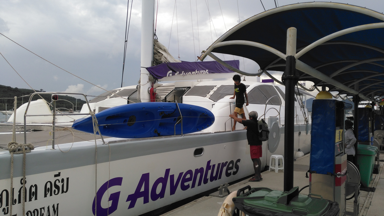 Des personnes montent à bord d'un grand yacht baptisé "G Adventures".