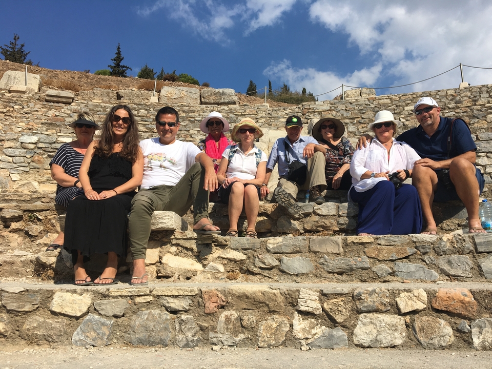 Group of people sitting on ancient stone steps.