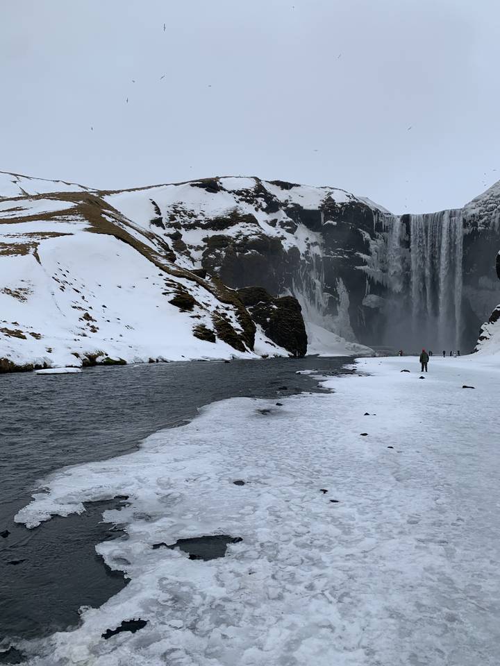 Waterfall surrounded by snow and ice in winter conditions.