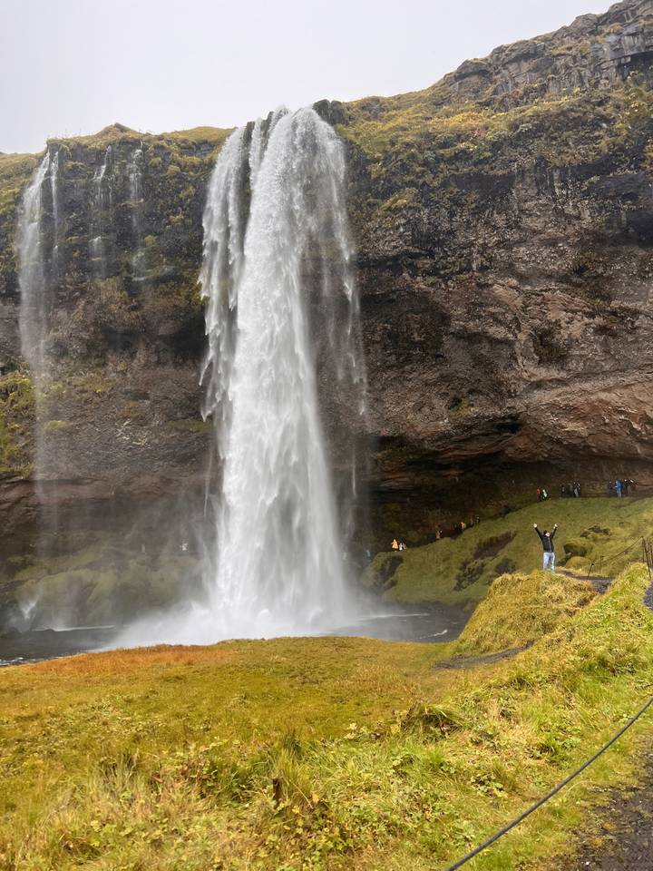 Waterfall taken from behind showing people walking underneath.