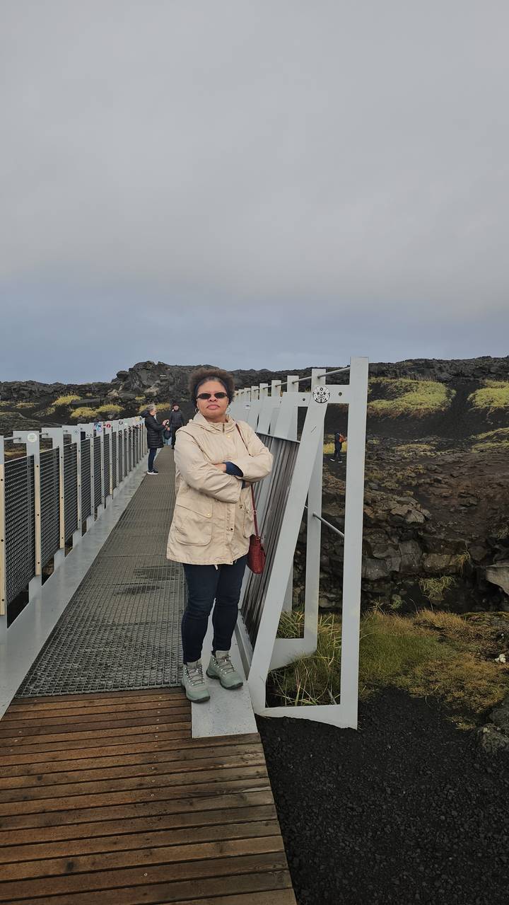 Person standing on a bridge over a rocky landscape.