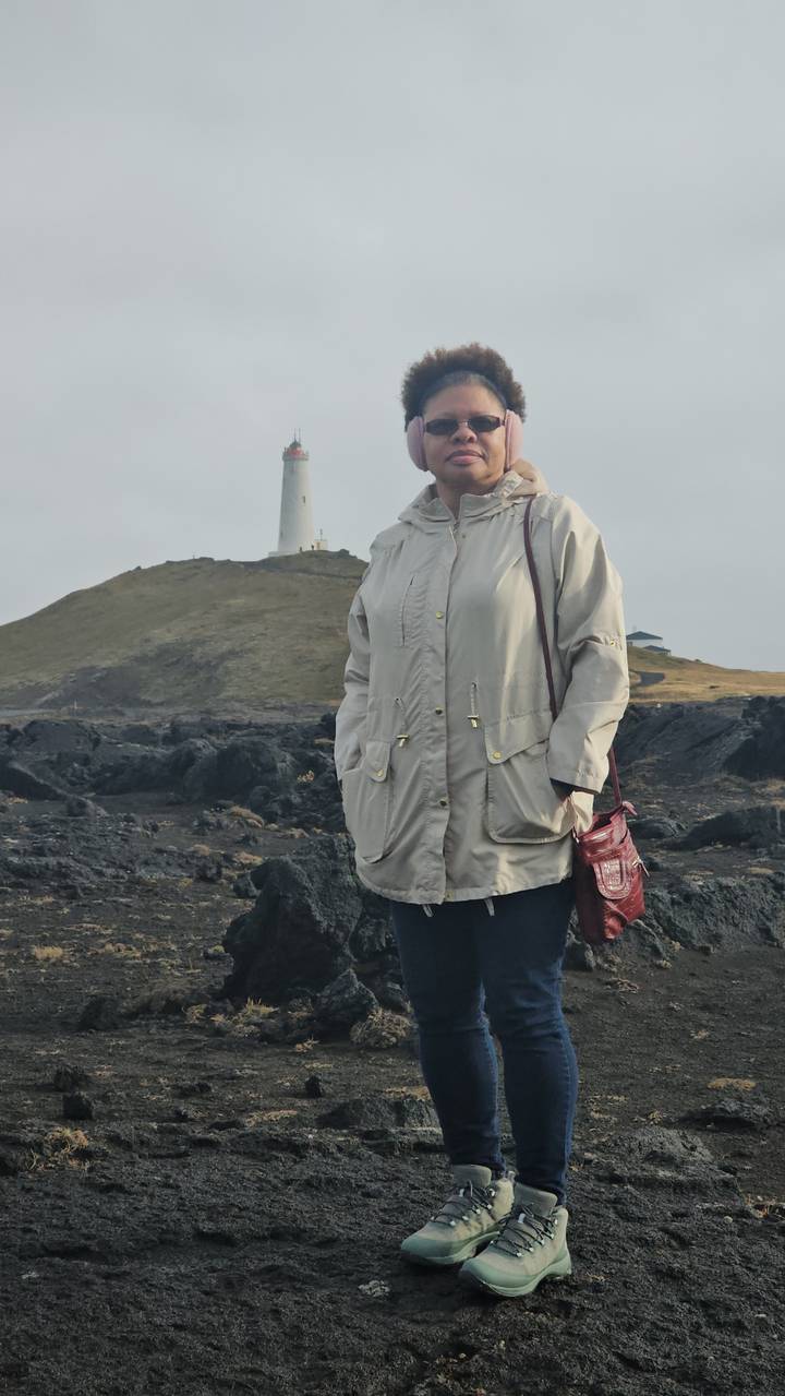 Person standing with a lighthouse in the background.