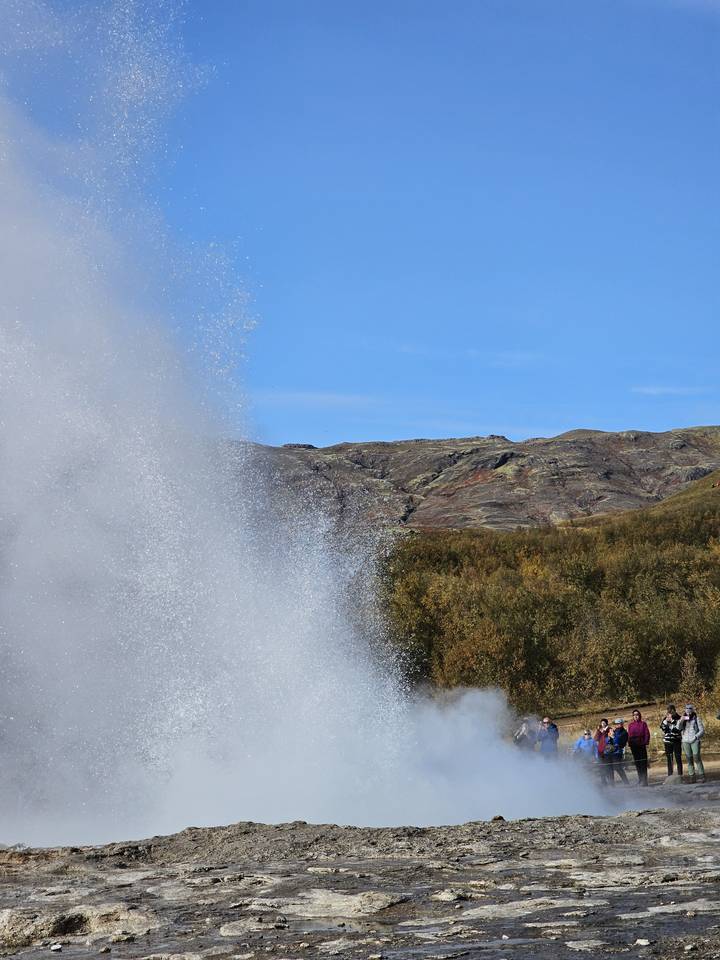 Geyser eruption in a rocky landscape.