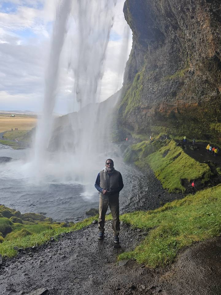 Man posing in front of a waterfall.