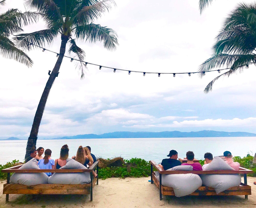 People sitting in a seaside cafe with a view of the ocean.