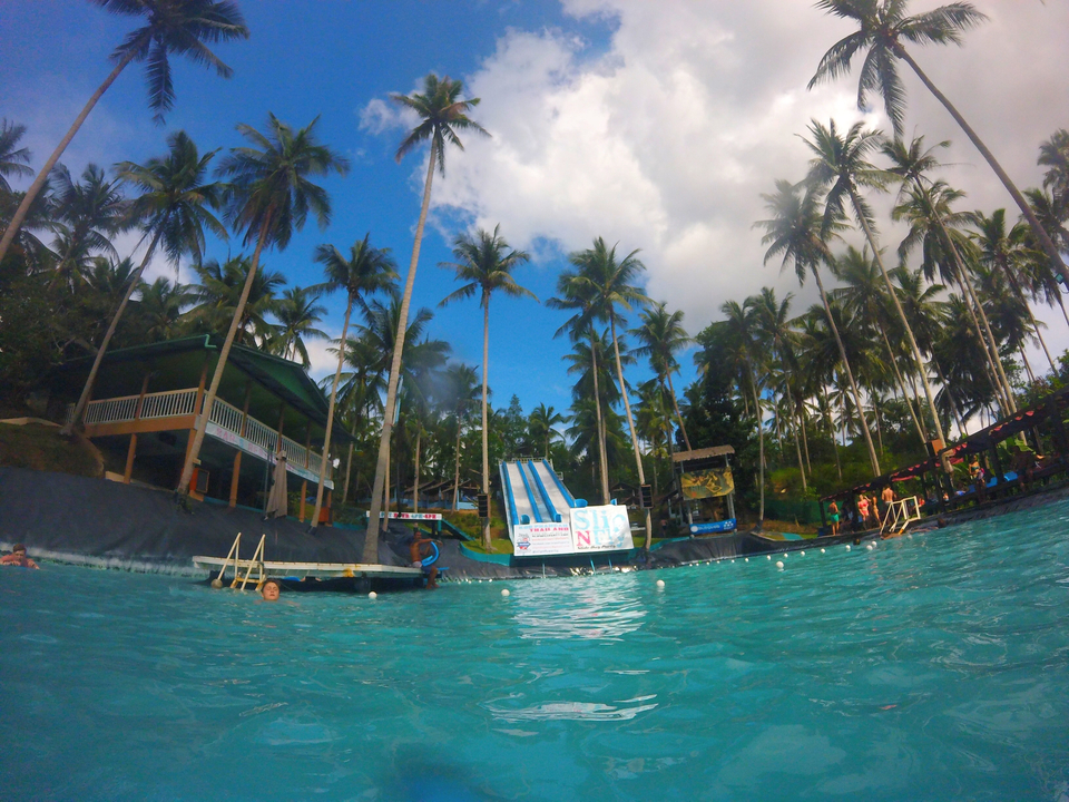 Outdoor water park with slides surrounded by palm trees.