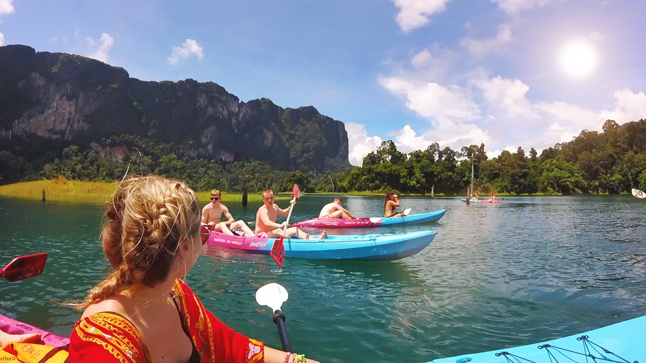 Group of people kayaking in a scenic lake with lush mountains.