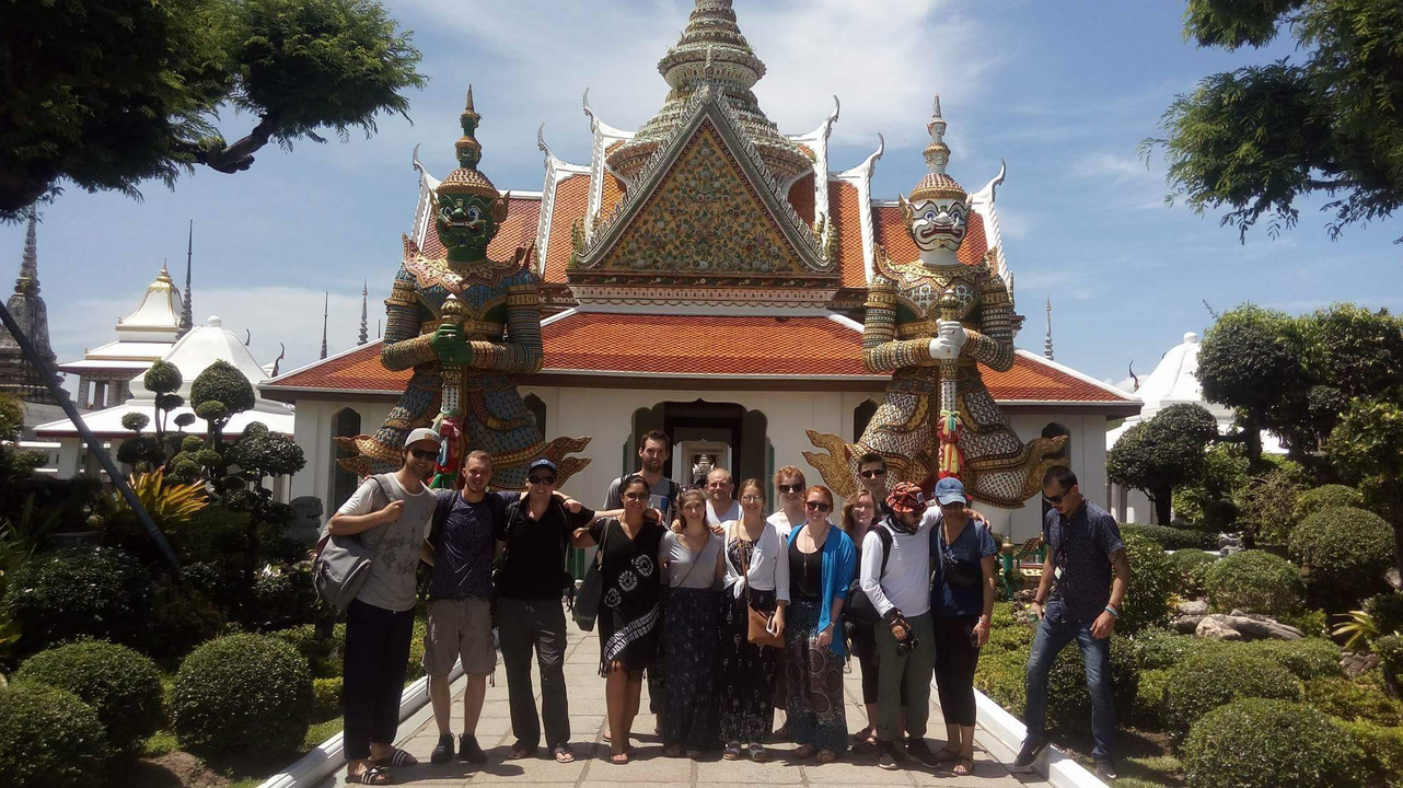 Group of tourists in front of a traditional temple with statues.