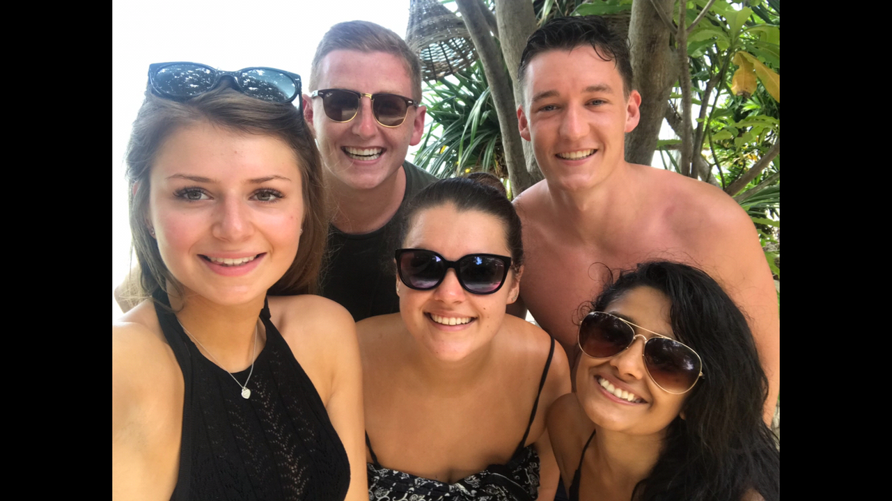 Group photo of five people outdoors wearing sunglasses.