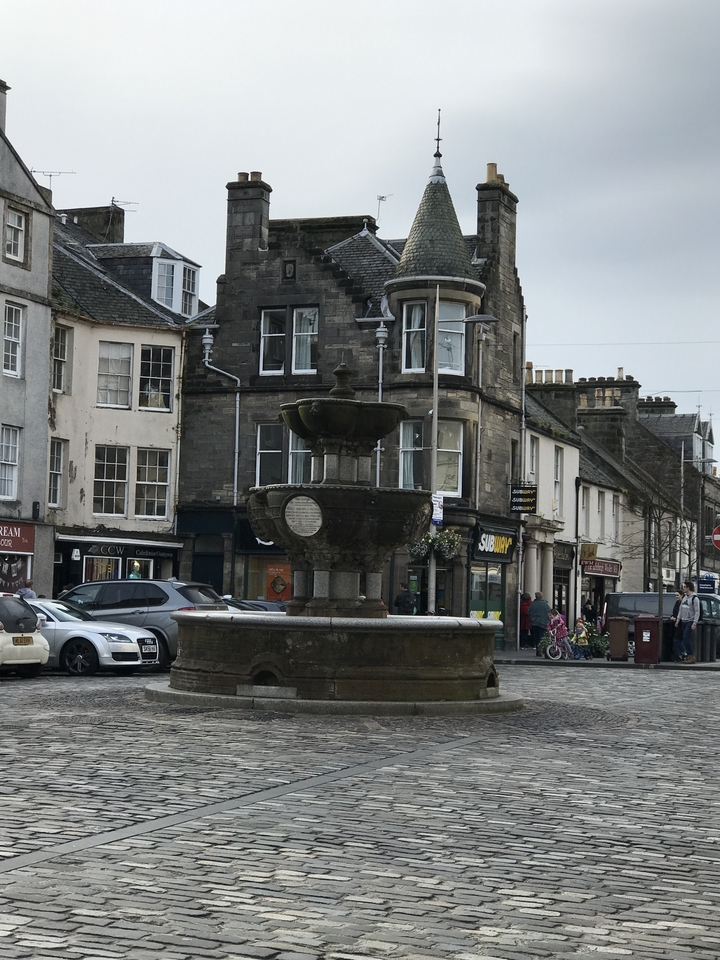 Old town square with a fountain and historic buildings.