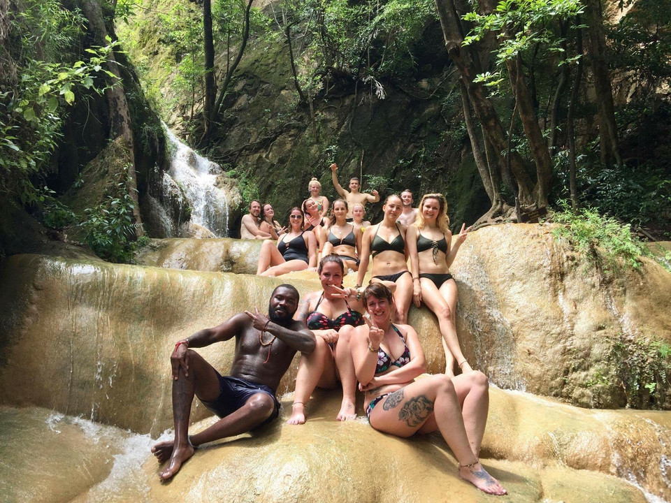 People enjoying a waterfall in a lush forest.