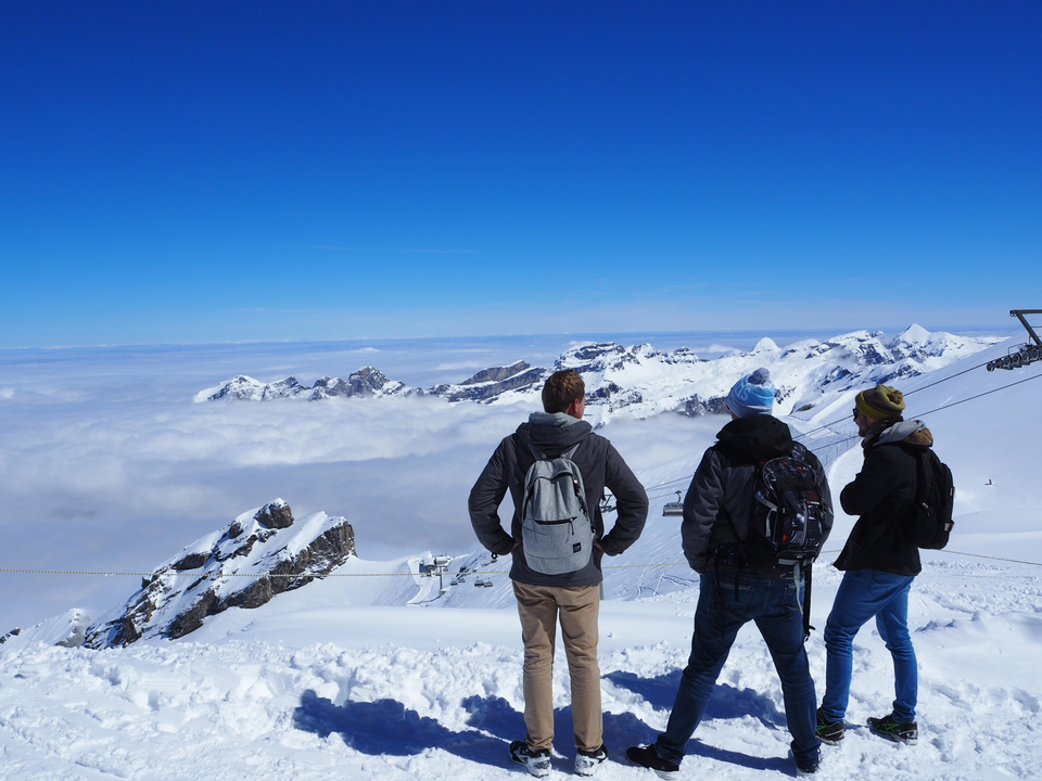 Three men overlooking a snowy mountain landscape.