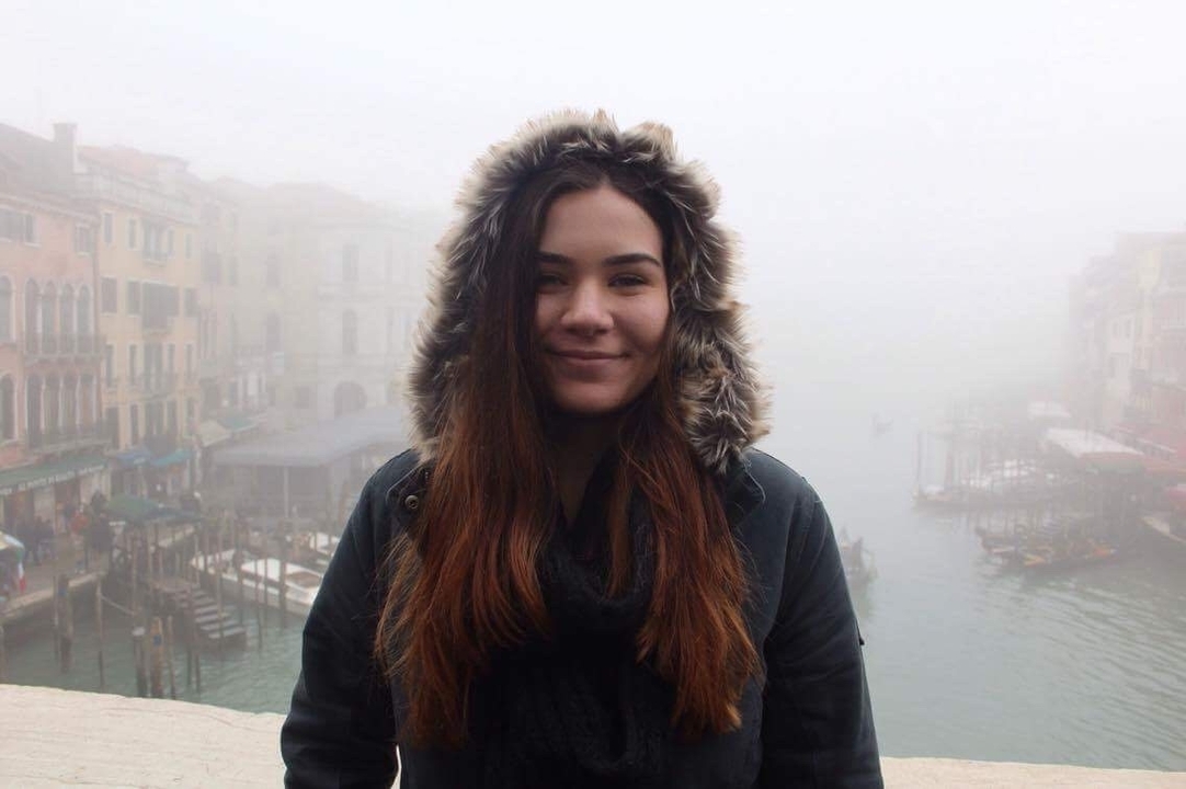 Woman smiling on a foggy bridge with canal view.