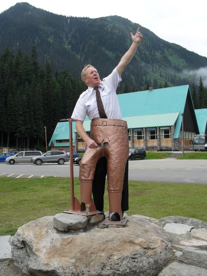 Touriste posant dans une sculpture de pantalon en cuivre surdimensionné dans un parking.