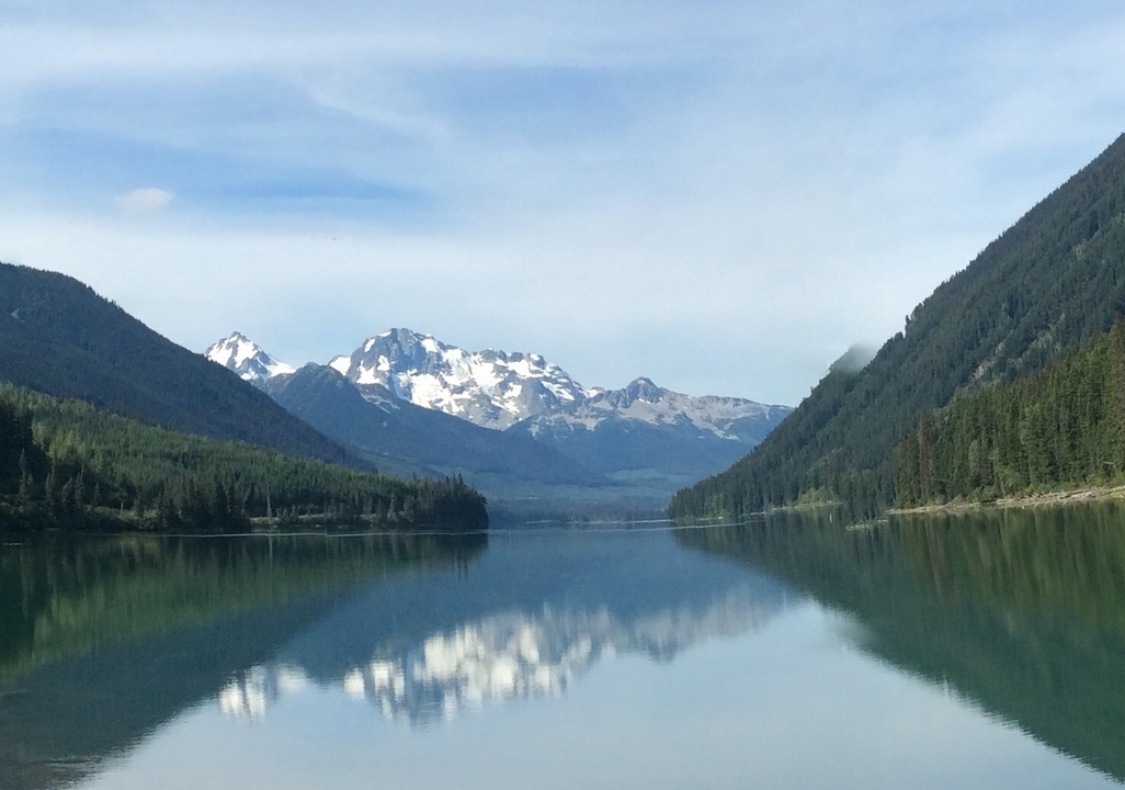 Calm lake reflecting distant snow-capped mountains.