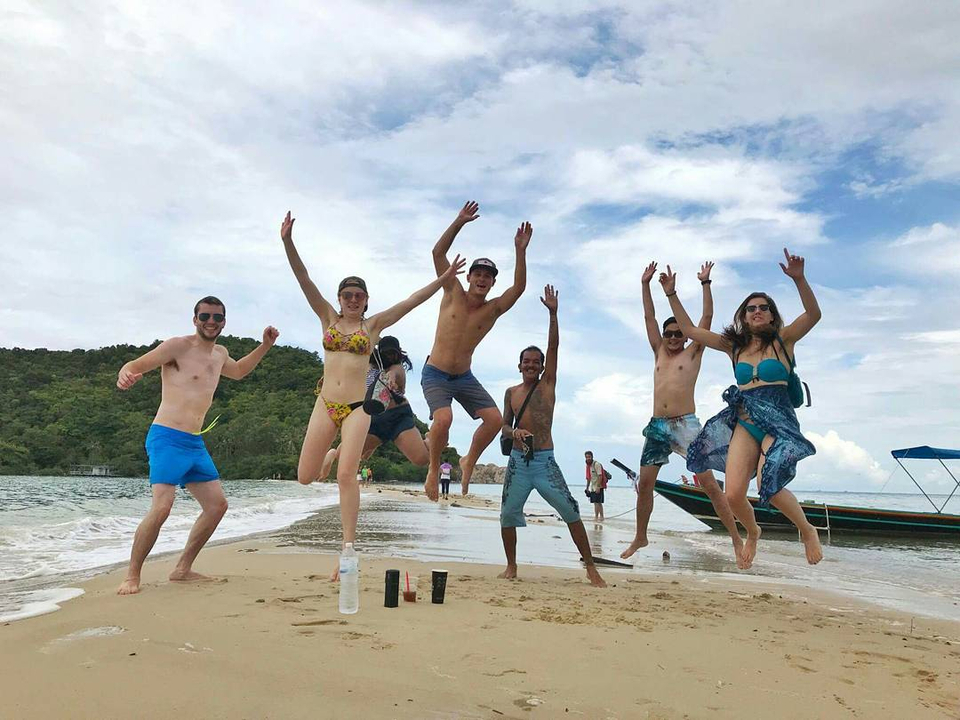 Group of people jumping on a sandy beach.