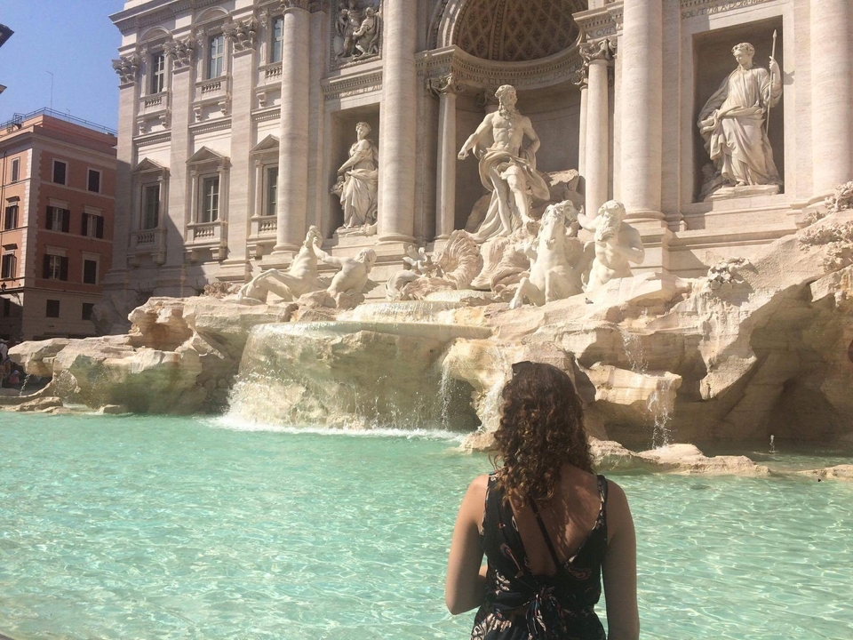 Woman looking at the flowing Trevi Fountain.