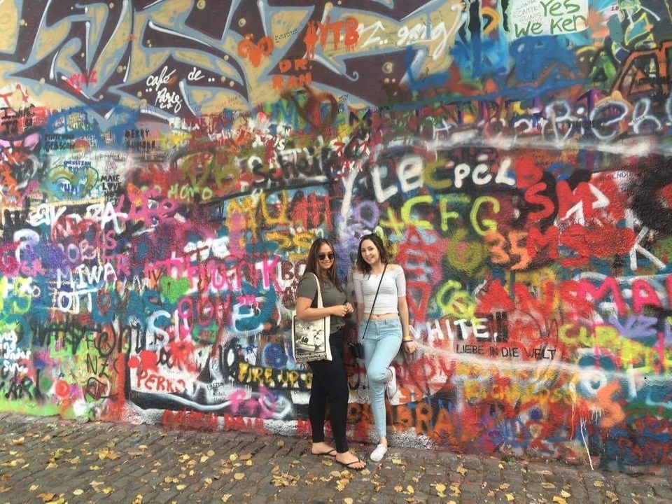 Two people standing in front of a colorful graffiti wall.