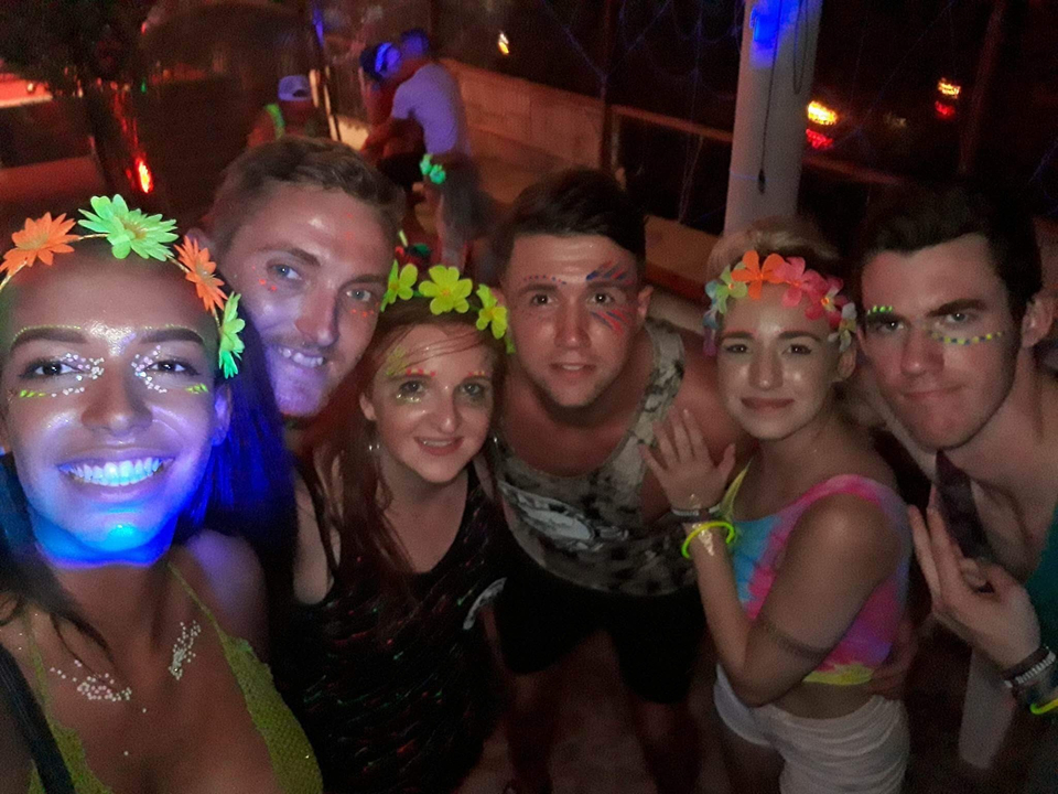 A group of people at a festive event with neon face paint.