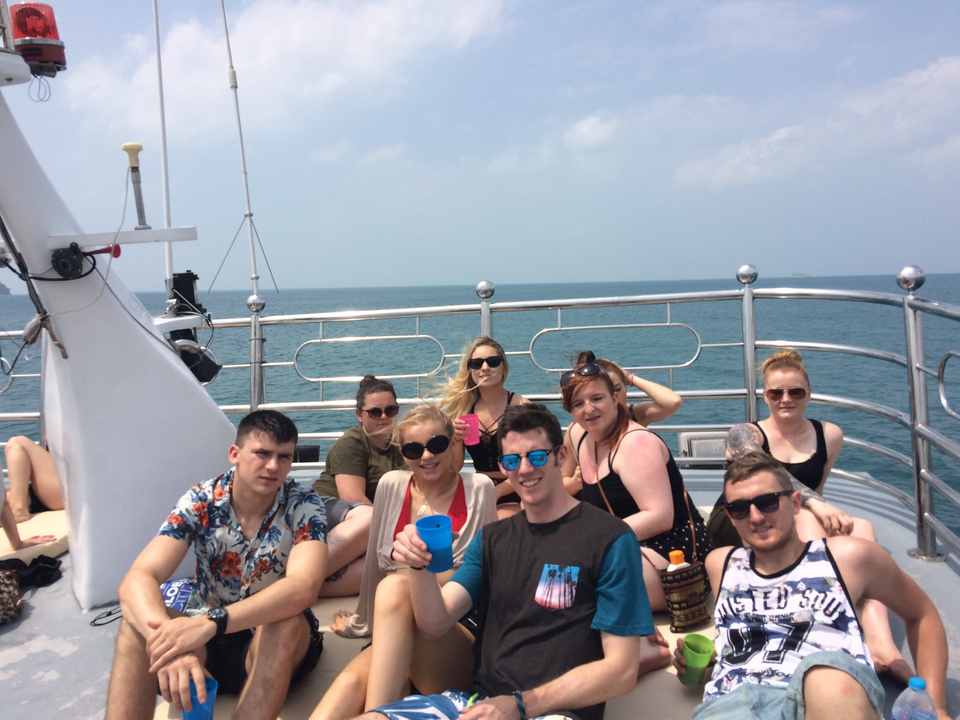 People on a boat posing for a group photo with the ocean in the background.