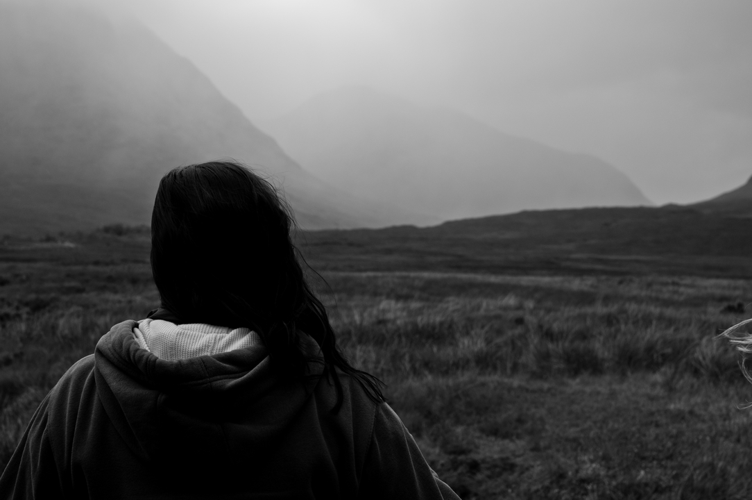 Person looking over a misty landscape of hills and valleys.