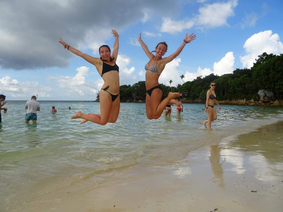 Two women jumping on a beach.