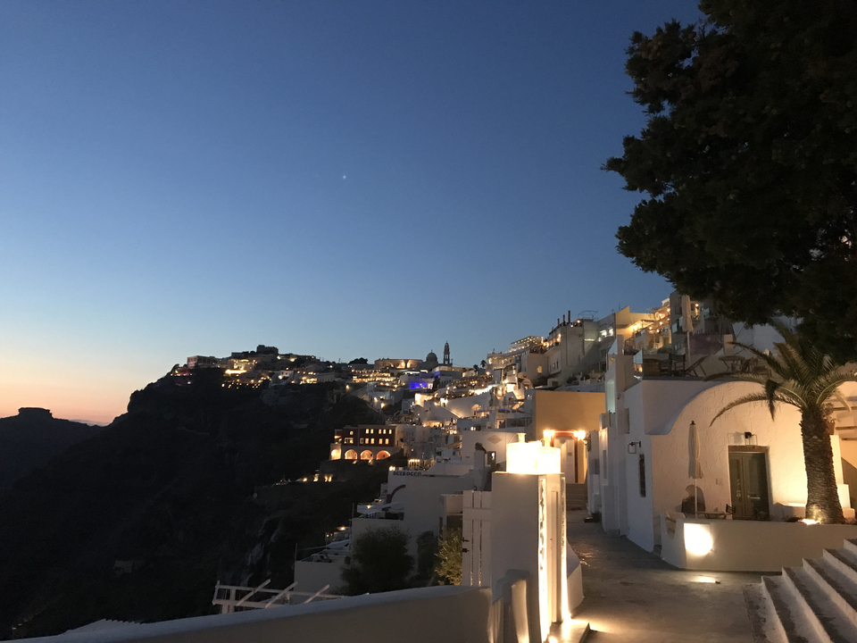 View of a lit-up Greek town at dusk.