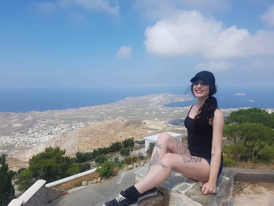 Woman posing with an expansive view of a coastline and town.