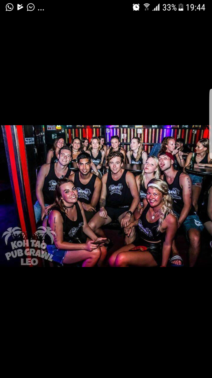 Group of people in a bar wearing matching tank tops.