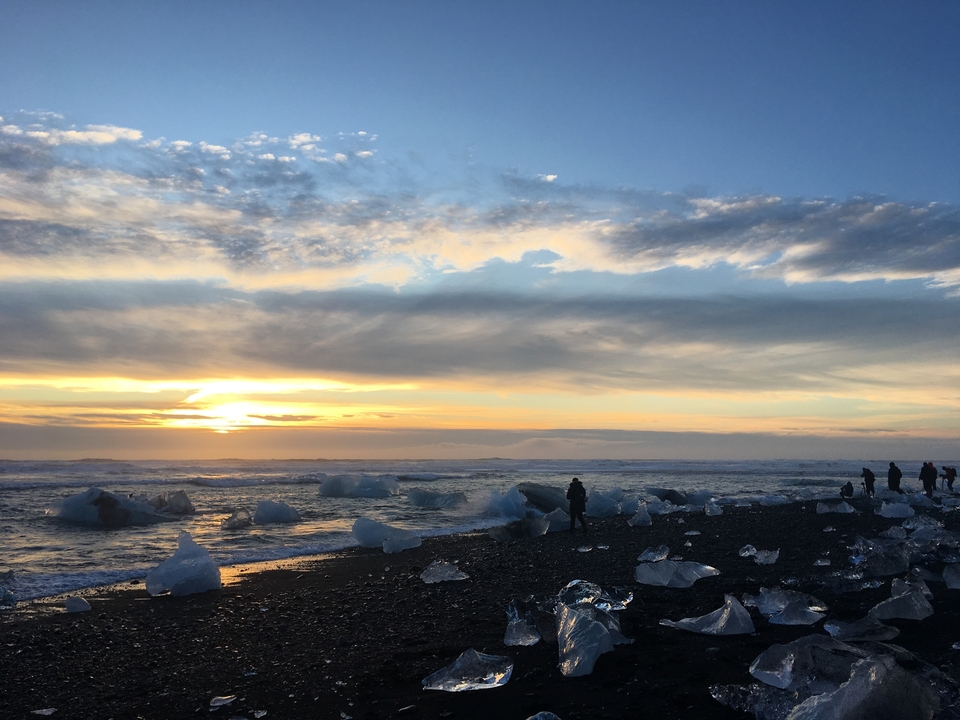 Scenic view of icebergs on a beach with a beautiful sunset.