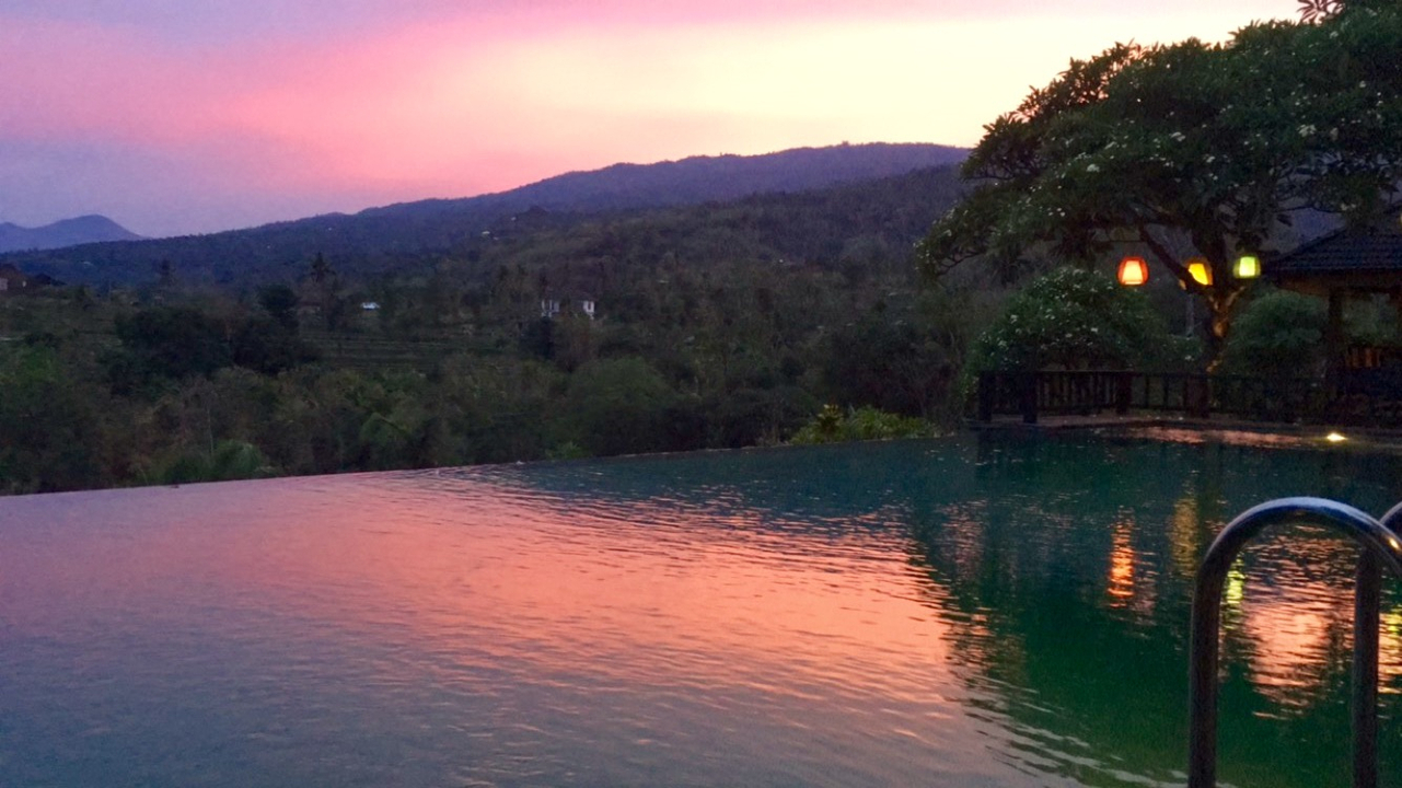 Infinity pool with a vibrant sunset reflecting on the water.