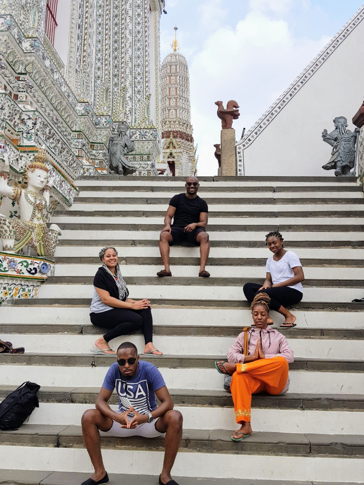 Group of people sitting on steps of ornate temple.