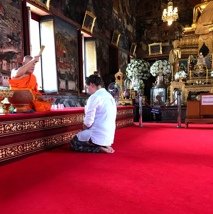 Person receiving a blessing from a monk in a temple.