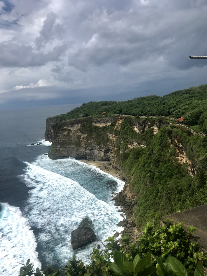 Scenic view of a rugged cliff coastline with waves crashing below.