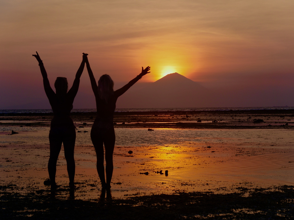 Silhouette of two people celebrating a sunset by the sea.