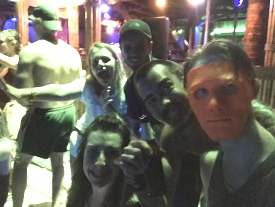 Group of friends at a dimly lit party, some with painted faces.