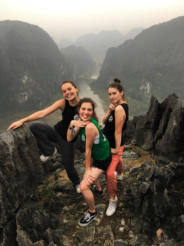 Three people posing on rocks with mountains in the background.