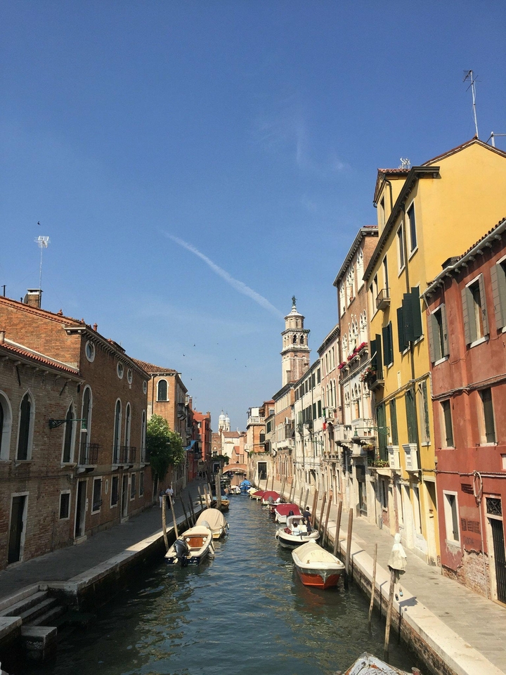 A view down a narrow street in Venice with traditional Italian architecture.