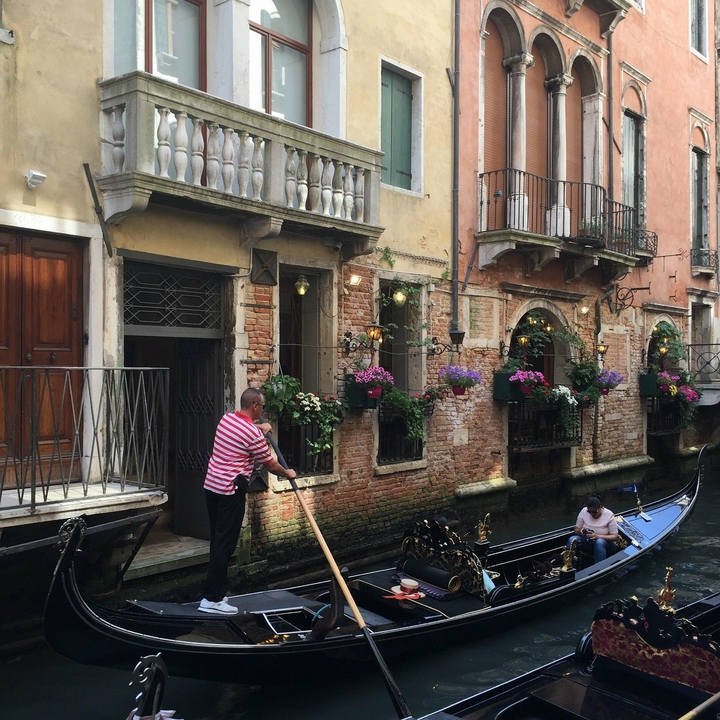 A gondolier rowing a gondola on a canal in Venice.
