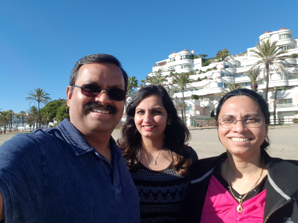 Three people on the beach with white buildings in the background.