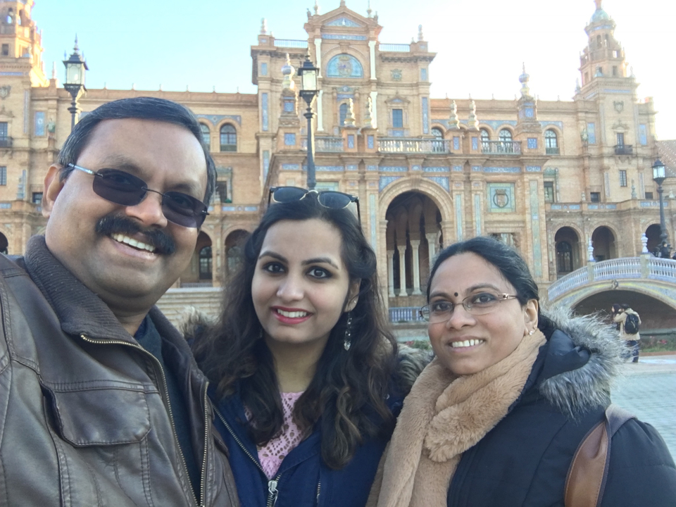 Three people smiling in front of a historic building.