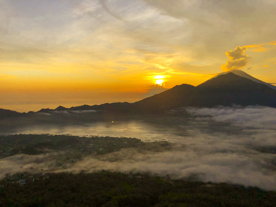 Sunrise over Mount Batur with clouds and mist.