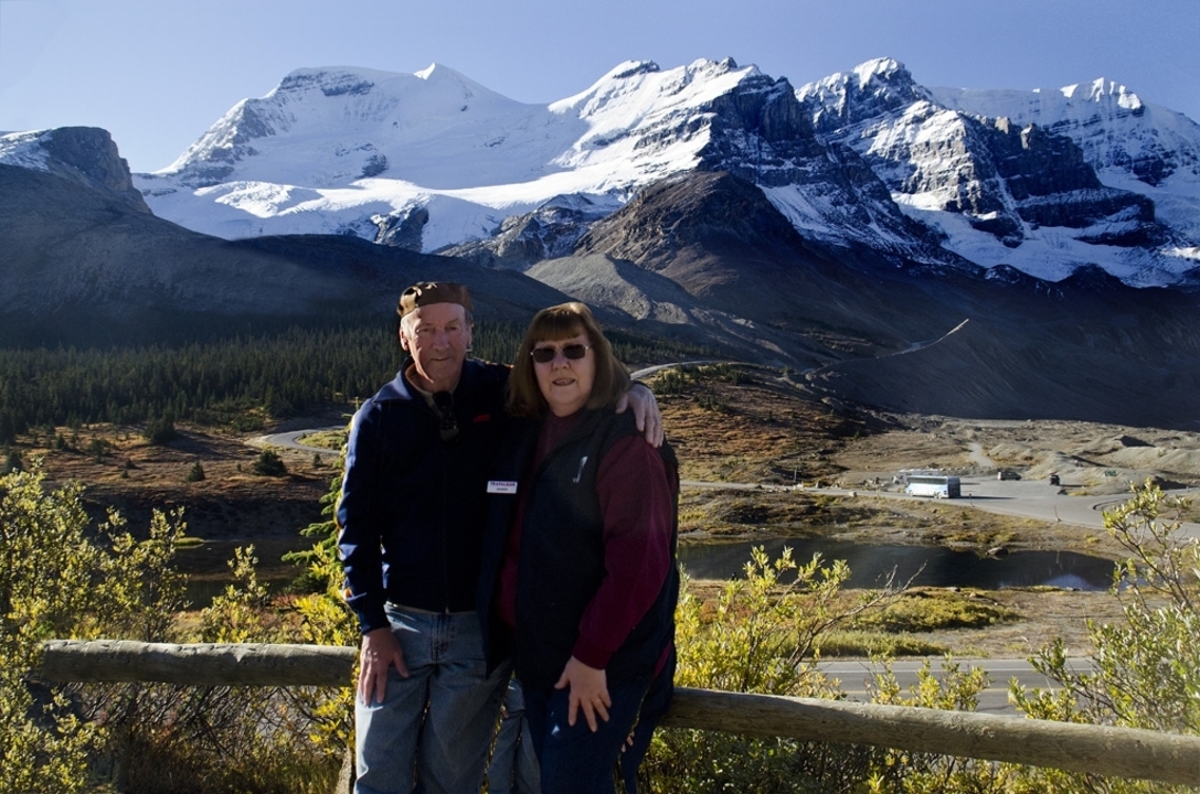 Two people posing with a mountainous backdrop.