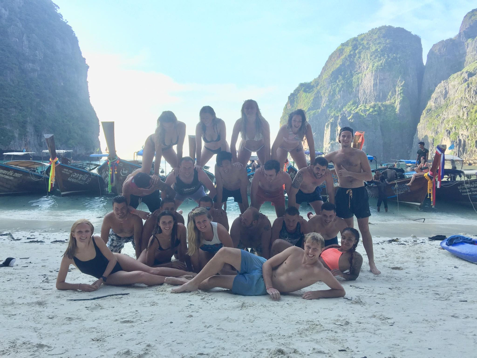 Large group performing a human pyramid on a beach.
