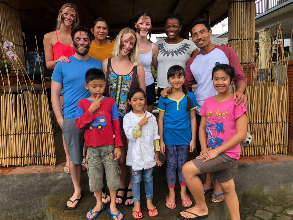 Group of adults and children posing in front of a bamboo structure.