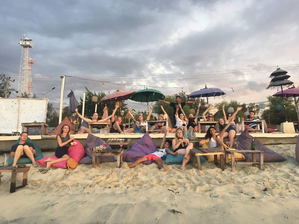 Group of people relaxing on beach seating with umbrellas.