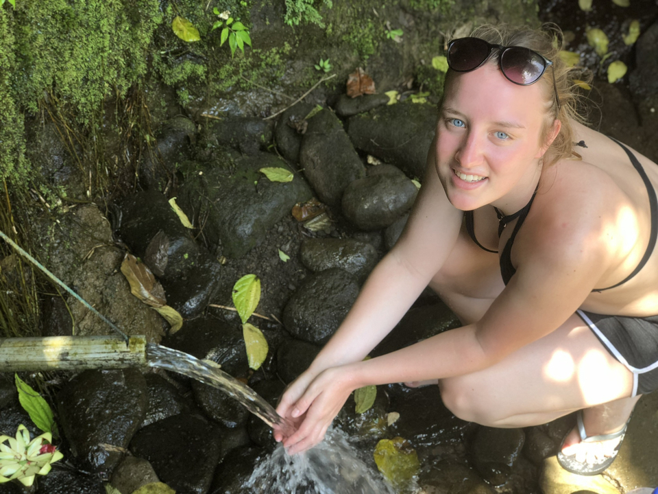 Person sitting by a natural water source.