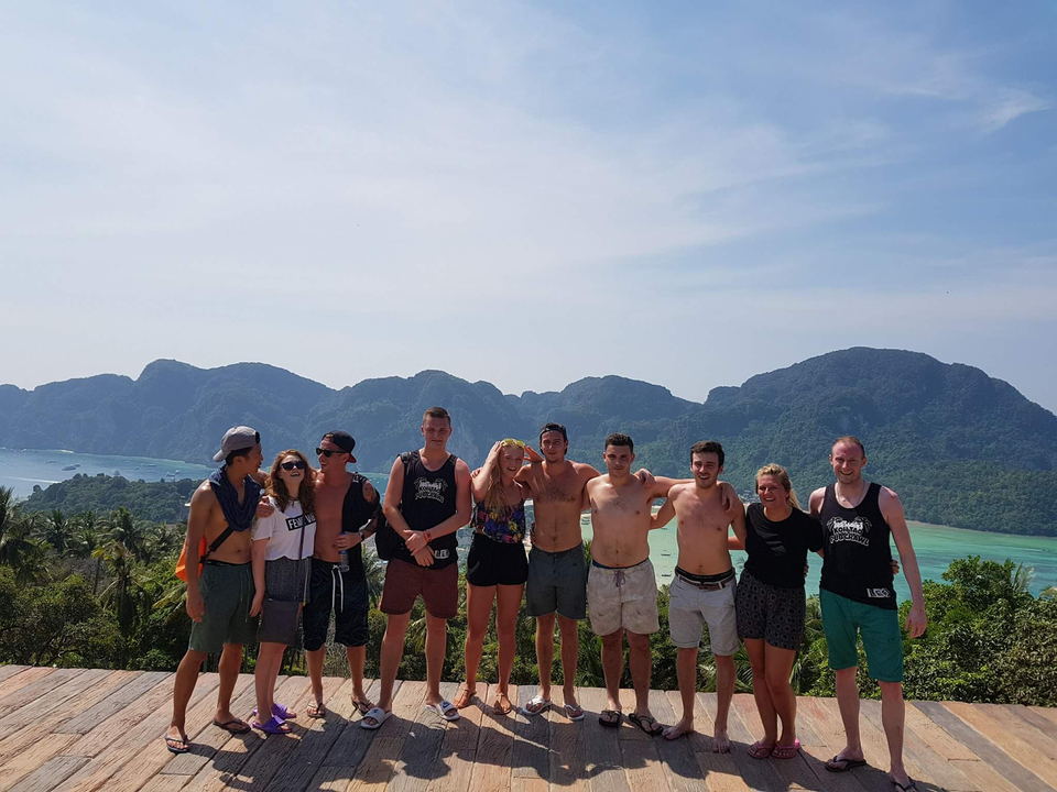 Group posing with mountains and ocean in the background.